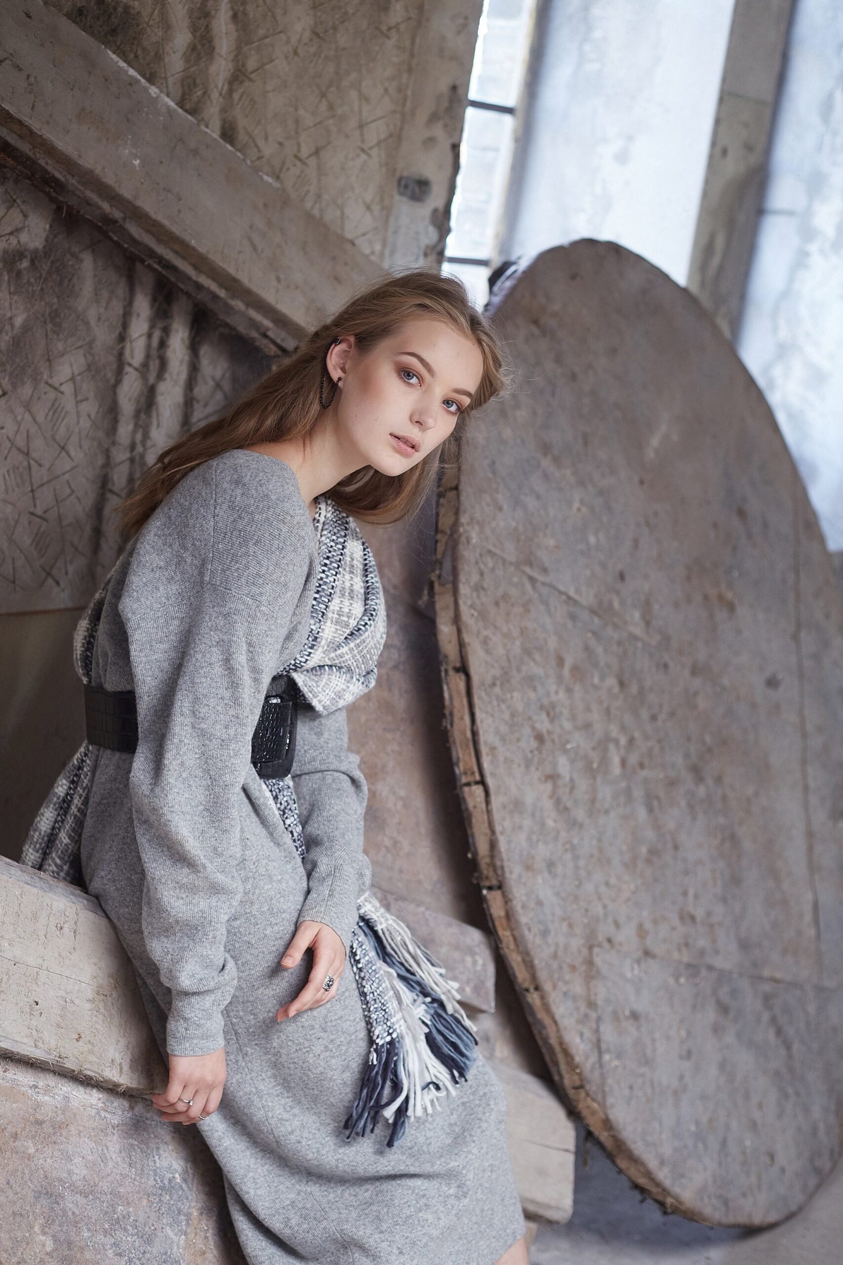 Slim woman in a long grey dress posing.